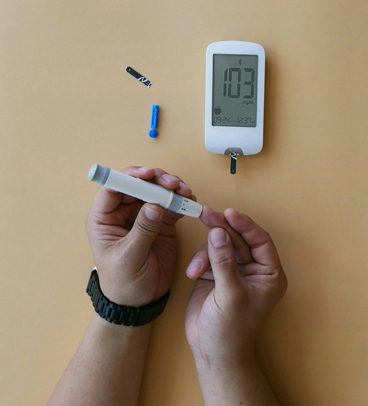 Person pricking finder to get a sample for blood glucose level