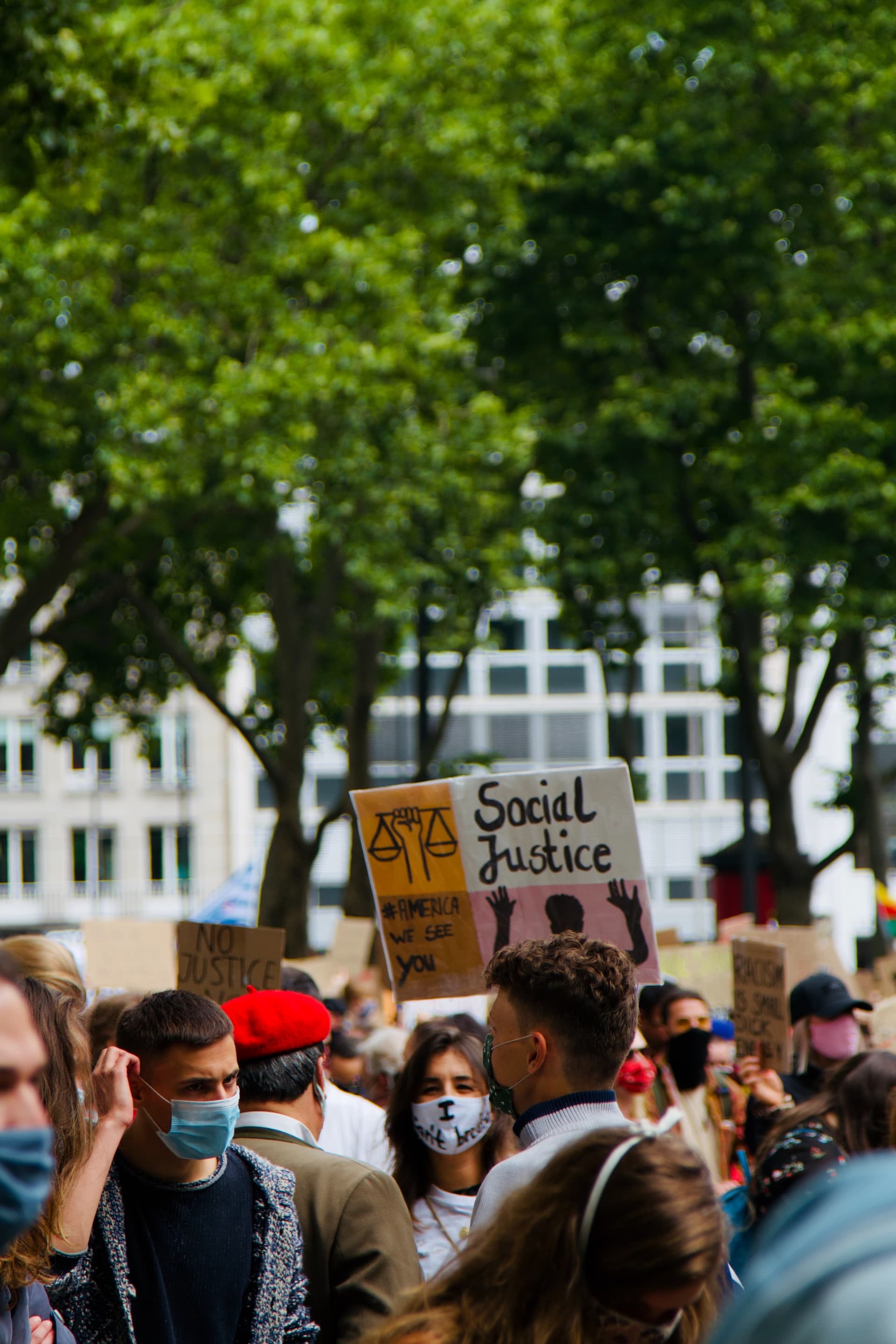 People gathering in a park during the day for a social justice rally.