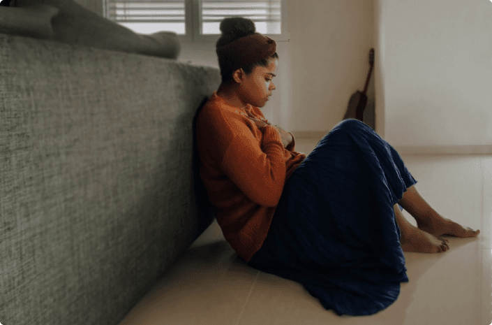 woman in orange long sleeve shirt sitting on gray couch