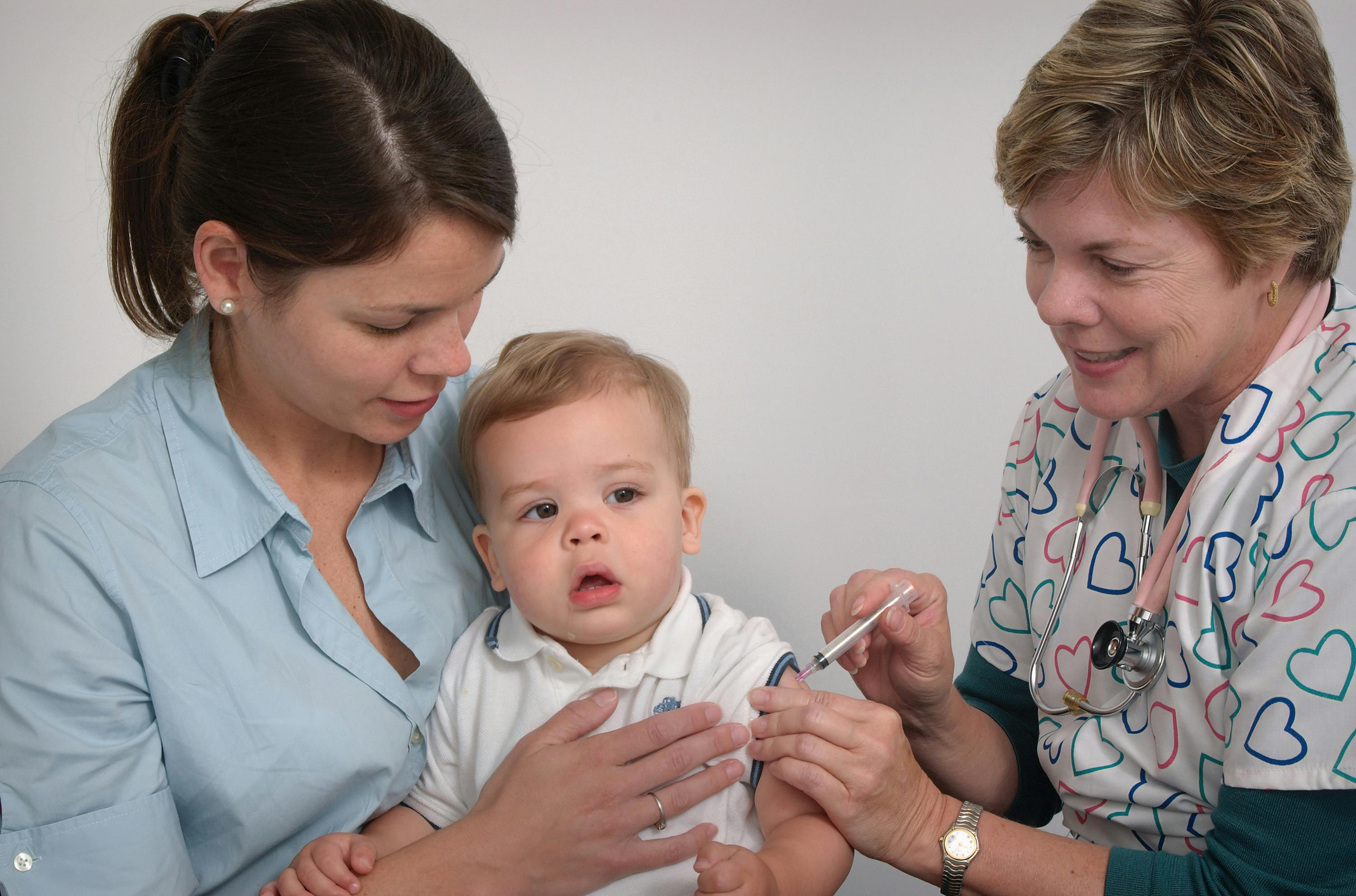 Baby or toddler receiving an immunization from a doctor while being held by parent