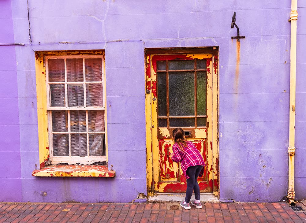 Young child in front of door with chipping paint
