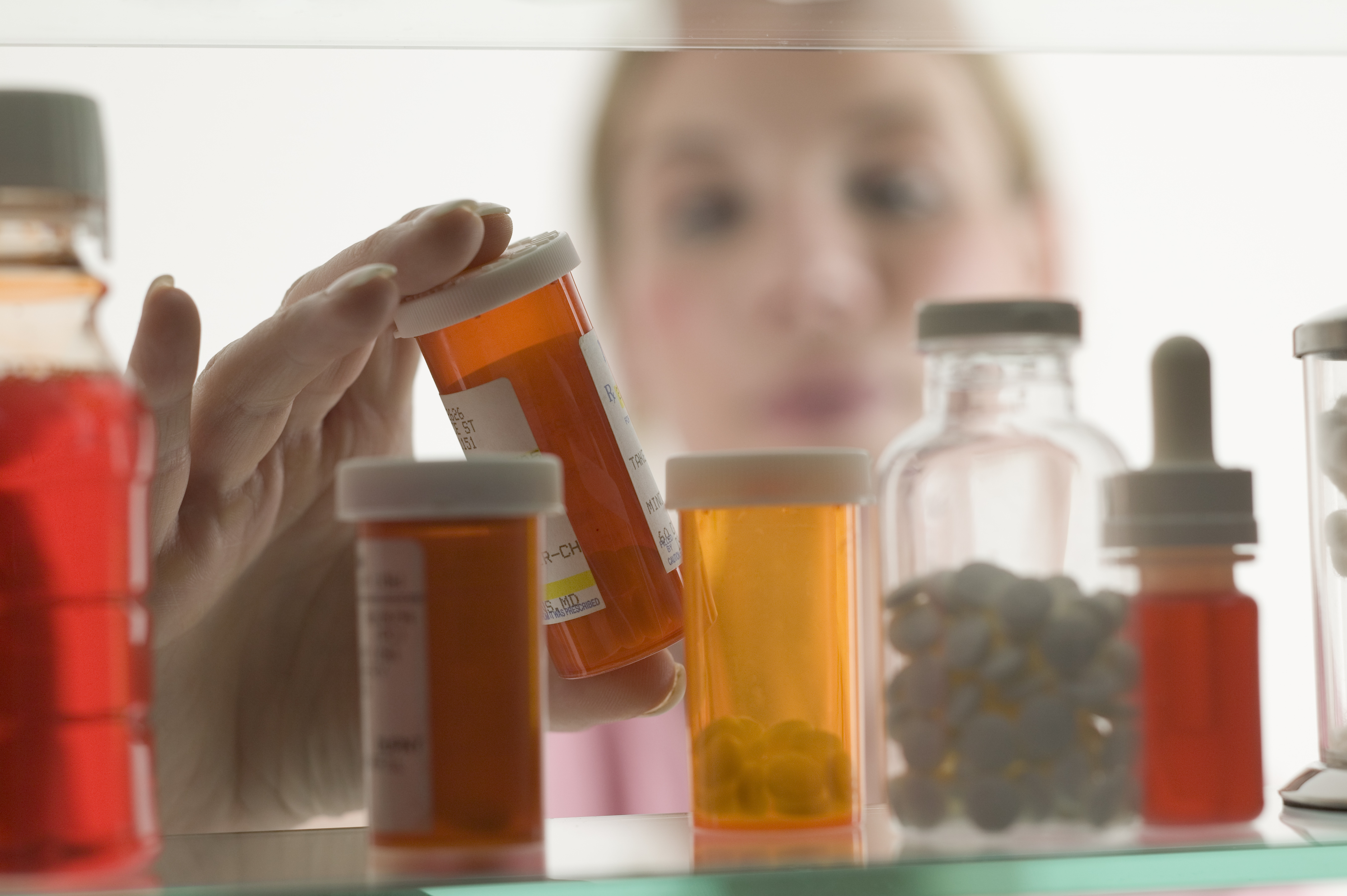 Pharmacist looking over collection of medicine bottles